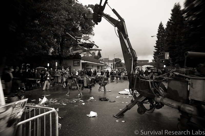 Big Arm tosses Stick Wheel Robot carcass over at the Running Machine